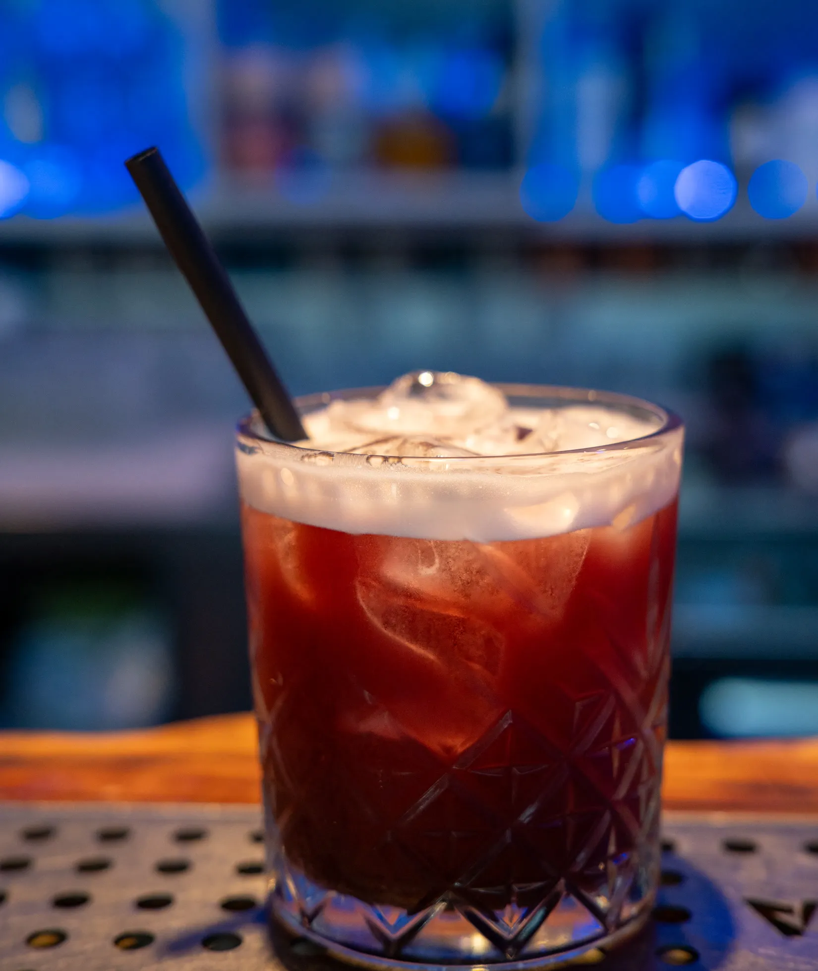 Cocktail rosso scuro con schiuma e cannuccia