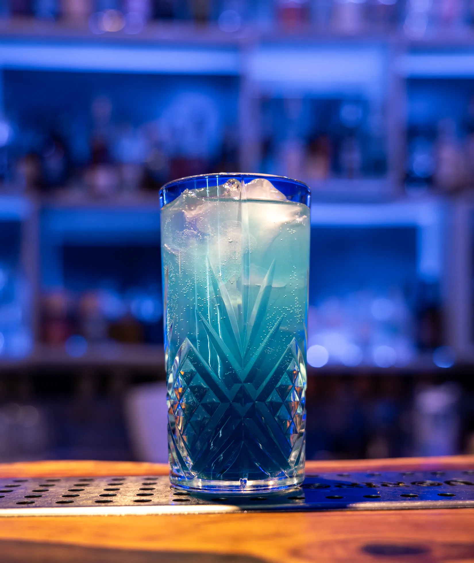 Cocktail azzurro in bicchiere alto sul bancone